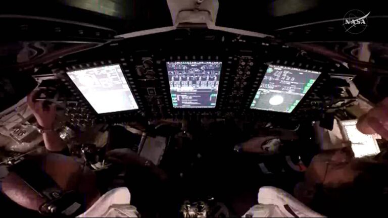 Uma vista por cima dos ombros dos astronautas da NASA Victor Glover (à esquerda) e Reid Wiseman (à direita), piloto e comandante, respectivamente, dentro da espaçonave Orion (NASA)
